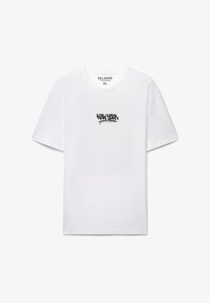 T-shirt bianca in cotone con maniche corte e scollo rotondo, con testo in stile graffiti nero sul davanti. Vestibilità rilassata, etichetta visibile all'interno.