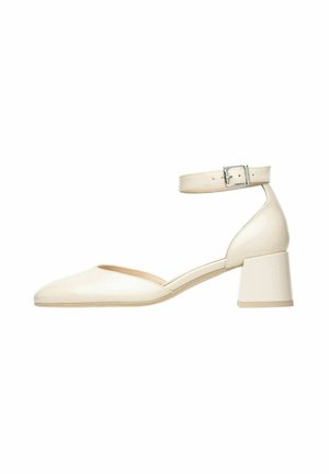 Talons en cuir verni crème avec un bout pointu, une sangle à la cheville ajustable et un talon bloc. Texture lisse avec un design minimaliste.