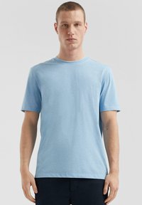 Jasnoniebieska bawełniana koszulka z krótkim rękawem, okrągłym dekoltem i gładką, miękką fakturą. Prosty fason, bez wzorów i akcentów.