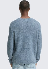 Blauwe gebreide trui met lange mouwen en een ronde halslijn, voorzien van een geweven patroon en een relaxte pasvorm aan de achterkant.