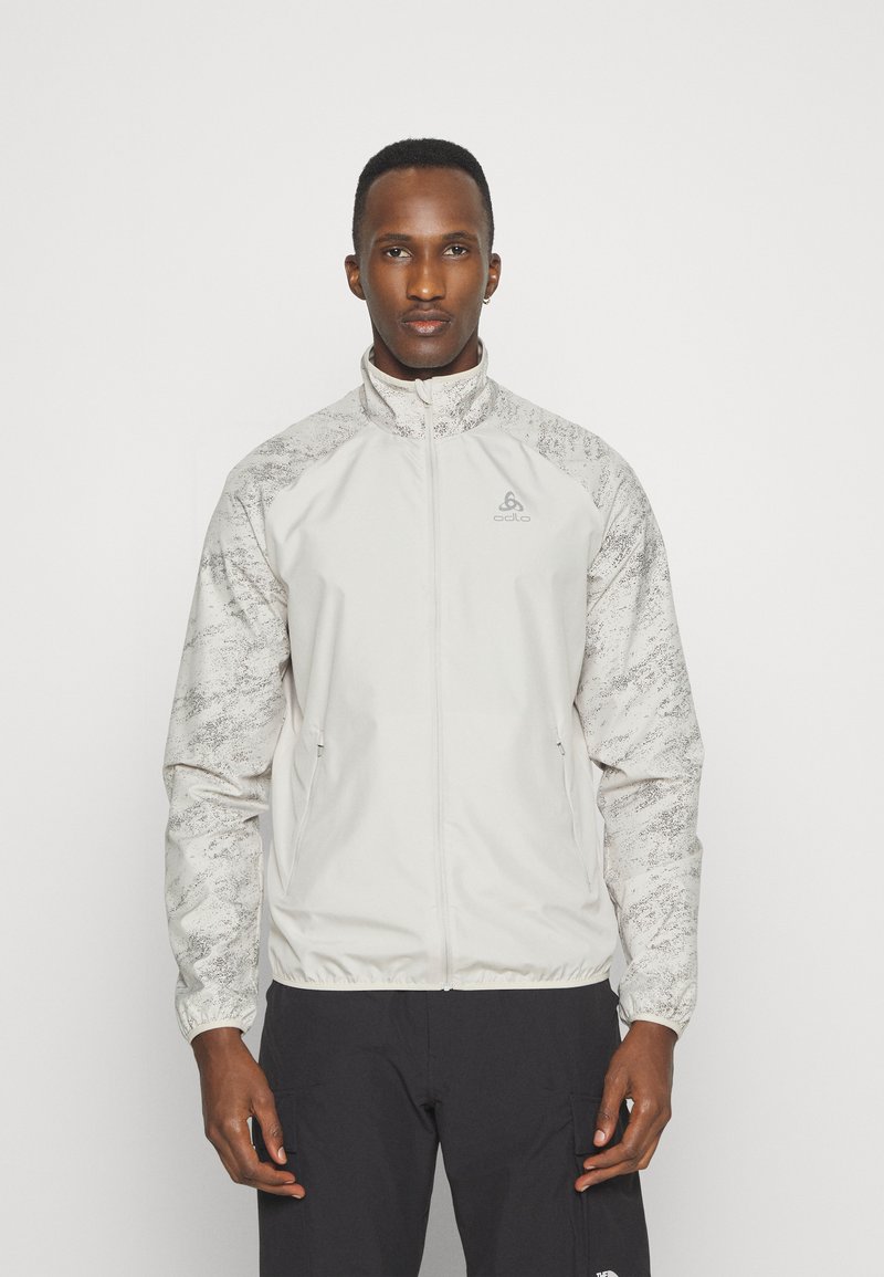 Leichte Jacke in Hellgrau mit strukturierten, gemusterten Ärmeln. Verfügt über einen Reißverschluss, einen hohen Kragen und elastische Bündchen, hergestellt aus atmungsaktivem Material.