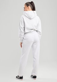 Sudadera gris y joggers a juego hechos de tela suave. La sudadera tiene capucha; los joggers cuentan con una cintura elástica y bolsillos laterales.