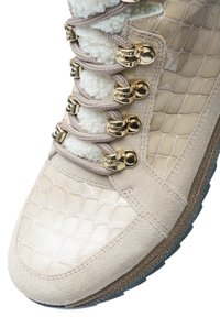 Sneaker beige texturé avec des panneaux en daim et en faux crocodile, lacets crème, œillets dorés et doublure de langue en fourrure blanche.