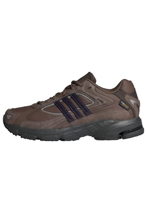Brauner Adidas-Laufschuh mit schwarzer Sohle, drei dunklen Streifen an der Seite, Schnürverschluss und Cordura-Stoffetikett in der Nähe der Ferse.