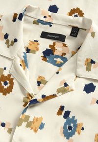 Kortærmet skjorte i et cremerfarvet stof med et blomsterdesign i marineblå, blå, orange og grøn. Inkluderer en klapkrave og mærkat.