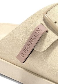 Sandalia tipo slip-on de ante beige con una suela gruesa, que presenta una tirante rosa etiquetada "D.FRANKLIN" para la identificación de la marca.