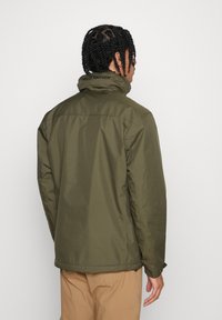 Giacca verde oliva con colletto alto, texture liscia e logo sulla schiena. Presenta una vestibilità dritta e dettagli di cucitura pulita.