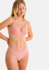 Ensemble de soutien-gorge et culotte assortie rose clair avec une bordure en dentelle sur les bords. Texture lisse avec un décolleté plongeant et des détails de couture décorative.