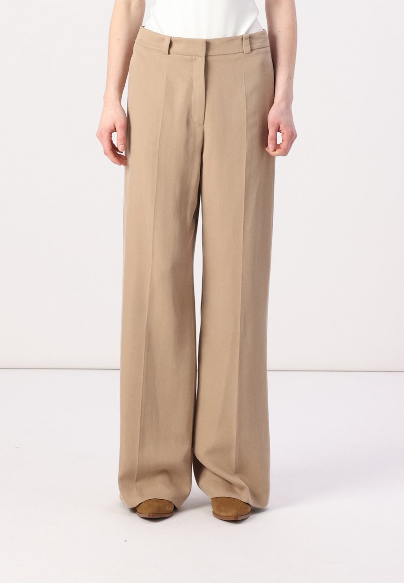 Beige wijde broek met een op maat gemaakte pasvorm, voorzien van voorplooien en een gladde textuur. Afgewerkt met een standaard tailleband en zakken.