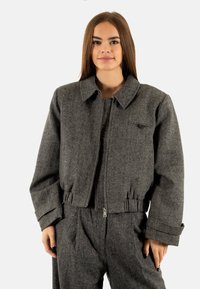 Grijze wollen mix cropped blazer met een kraag, ritssluiting vooraan en elastische zoom. Beschikt over een enkele borstzak en gestructureerde mouwen.