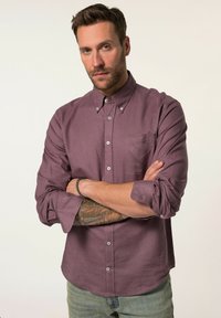 Chemise à manches longues, boutonnée, de couleur bourgogne atténuée, fabriquée dans un tissu texturé, avec une poche sur la poitrine et des manches retroussées.