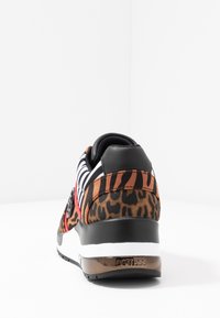 Baskets avec un talon en cuir noir, imprimé animal marron et orange, dessus à motif rayé en noir et blanc, accents rouges et logo brillant.