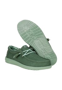 Zapatillas de lona verdes con una superficie texturizada, cordones verde claro y un interior estampado. Suela de goma gruesa y flexible con patrones de estrellas.