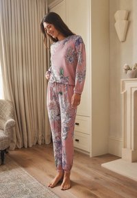 Ensemble de vêtements d'intérieur à motif floral dans des tons roses doux, comprenant des manches longues, des poignets élastiques et une taille à cordon pour plus de confort.