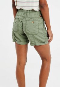 Shorts vert olive en tissu doux et léger. Équipés d'une taille élastique, de deux poches arrière avec fermetures à bouton et de revers. 
