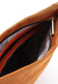 Interno di una borsa intrecciata arancione testurizzata con fodera grigia e diversi scomparti, tra cui tasche con cerniera. Chiusura con zip nella parte superiore.