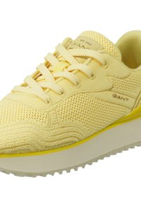 Gelbe Netz-Sneaker mit strukturiertem Design, Schnürverschluss und einer weißen Zwischensohle, die mit einem gelben Streifen akzentuiert ist. Markennamen an der Seite sichtbar.