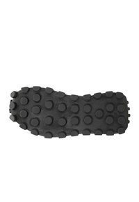 Sole di scarpa in gomma nera con superficie testurizzata e nubi circolari per la trazione. La forma è leggermente curva con un bordo liscio.