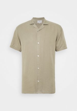 Chemise beige à manches courtes avec boutons et col camp, fabriquée en tissu léger, présentée sur un fond uni.