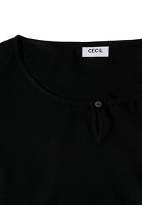 Zwarte shirt met ronde halslijn, kleine knoopdetails en eenvoudige stiksels. Merktag "CECIL" zichtbaar bij de hals. Zachte textuur.