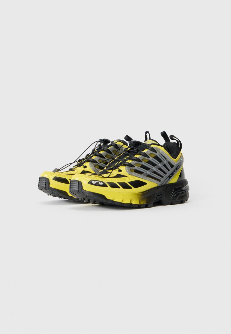 Par af gule og sorte trailrunning sko med grå mesh og hurtiglåsesystem på en hvid baggrund.