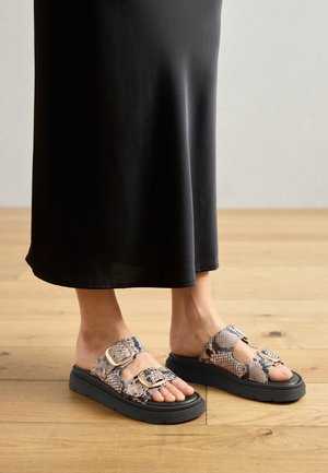 Zwei offene Sandalen mit Schlangenledermuster, ausgestattet mit zwei verstellbaren Riemen, einer stabilen schwarzen Sohle und einer strukturierten Oberfläche.