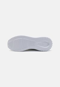 Egy sneaker talpa, fehér gumiból készült, texturált mintázattal és bordázással a tapadás érdekében. Lapos forma, látható logó nincs.