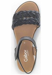 Sandal in pelle nera con cinturini superiori intrecciati, cinturino alla caviglia regolabile e una soletta imbottita color testa di moro. Logo Gabor visibile sulla soletta.