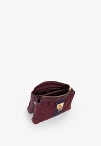 Borsa sintetica bordeaux con sofisticate embossing floreali, doppie tasche con zip e un logo dorato su una striscia blu navy.