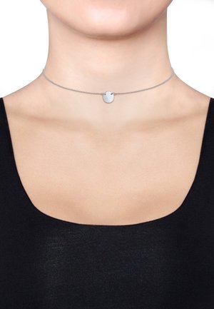 Silberne Choker-Halskette mit einem texturierten runden Anhänger, ausgestattet mit einer feinen Kette und glatter Oberfläche, getragen über einem dunklen Oberteil.