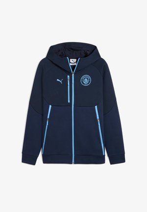 Sudadera con capucha azul marino con cremallera y un acento azul. Cuenta con cuello alto, dos bolsillos con cremallera y un logo del Manchester City en el pecho. Tejido suave.