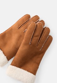 Guanti in suede marrone con polsino in finta pelliccia crema. Progettati con quattro dita e un pollice, presentano cuciture sottili lungo i bordi.