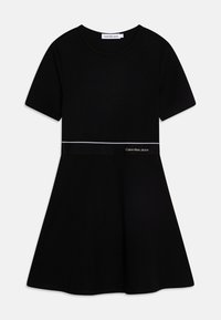 Czarna sukienka t-shirt w miękkiej bawełnie, z krótkimi rękawami, dopasowanym topem, rozkloszowanym dołem oraz białym akcentem z logo Calvin Klein Jeans na talii.