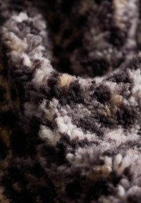 Weiche, plüschige Stoffe in Schattierungen von Dunkelpurpur, Grau und Creme, mit einem gemusterten Design und einer flauschigen, strukturierten Oberfläche.