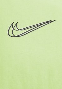 Ljusgrön tyg med en svart Nike swoosh-logotyp. Texturen är slät med ett subtilt ribbat mönster.