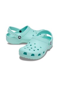 Calzado tipo zueco en un tono azul claro, fabricado con material flexible, con agujeros de ventilación, una plantilla contorneada y una correa trasera para un ajuste seguro.