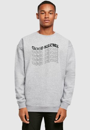 Gray sweatshirt features a printed multi-layered text design stating "GOOD KARMA" in varying fonts and styles on the front.