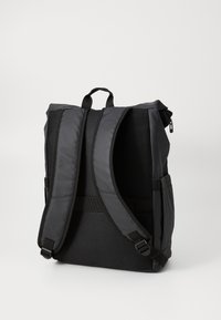Sac à dos noir avec des bretelles rembourrées, des panneaux en mesh, une fermeture éclair et une poignée supérieure renforcée pour le transport.