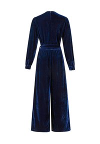 Combinaison en velours bleu marine à manches longues, taille cintrée et pantalon à jambes larges. Caractérisée par une texture lisse et une fermeture éclair au dos.