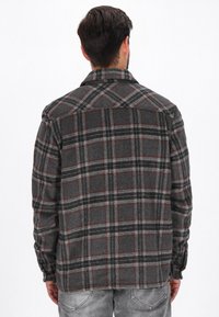 Cămașă din flanel cu carouri gri, accente roșii și negre, mâneci cu butoni și guler. Textură moale și croială lejeră. Vedere din spate afișată.