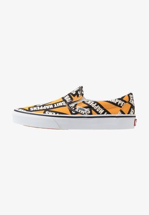 Chaussure Vans slip-on avec motif géométrique orange, noir et blanc, arborant la phrase « Shit Happens » répétée sur toute la tige en tissu.