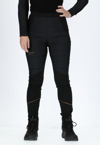Schwarze Outdoor-Hosen mit einer gesteppten Textur, schmaler Schnitt und kontrastierenden matten Abschnitten. Verfügt über goldene Akzente und Reißverschlusstaschen auf der Vorderseite.