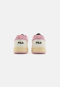 Weiße und pinke Sneakers mit einem Obermaterial aus strukturiertem Leder, Gummisohle und einem auffälligen schwarzen "Fila"-Logo an der Ferse und Rückseite des Schuhs.