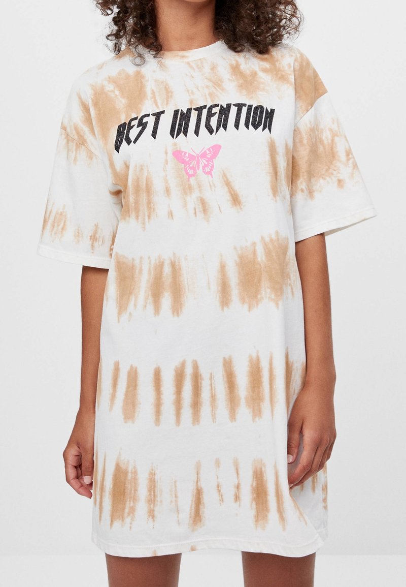 Weißes Baumwoll-T-Shirt-Kleid mit braunem Batikmuster, kurzen Ärmeln, Rundhalsausschnitt und bedrucktem Text "BESTE INTENTION" mit einer pinkfarbenen Schmetterlingsgrafik.