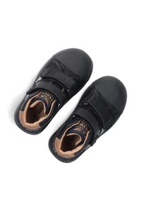 Zwarte leren schoenen met twee klittenbandsluitingen, ronde neus, gevoerde binnenkant en rubberen zool; heeft tan accenten op de voering en inlegzool.