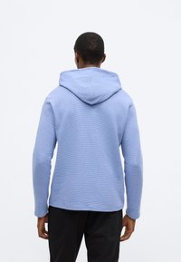 Sweatshirt azul claro com capuz, tecido texturizado, mangas compridas e corte descontraído. Apresenta um capuz espaçoso e bainha direita.