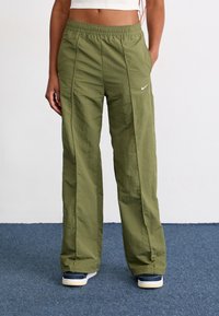 Grønne, lette cargo-bukser med elastisk liv og sidesømme. Har et lille hvidt Nike-logo på venstre lår.