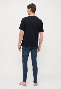 Schwarzes T-Shirt mit kurzen Ärmeln kombiniert mit dunkelblauen, gemusterten Leggings, die ein strukturiertes Design, eine enge Passform und enganliegende Knöchelbündchen aufweisen.