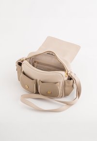 Beige læder crossover taske med struktureret overflade, guldfarvede metaldele, lynlåslukning og to frontlommer. Indvendigt inkluderer den en ekstra lomme.