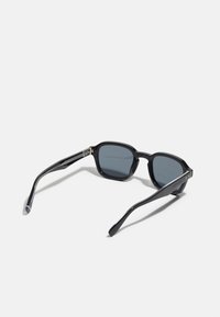 Ochelari de soare rectangulare negre cu lentile gri, având rame groase și brațe elegante. Accentele metalice de pe balamale adaugă detalii subtile.